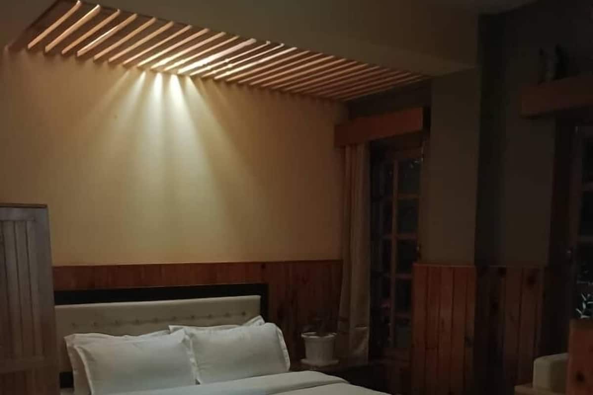 Ein ordentlich bezogenes Bett mit einer gestreiften Decke, einem hölzernen Kopfstück und einer Deckenleuchte.
