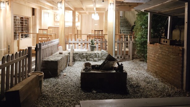 A cozy, well-lit outdoor seating area with wooden furniture and a white picket fence. - UV INN (Thimphu)