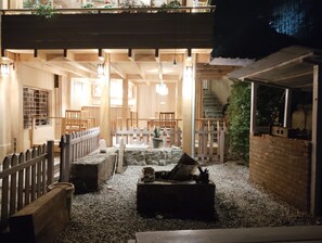 A cozy, well-lit outdoor seating area with wooden furniture and a white picket fence. - UV INN (Thimphu)