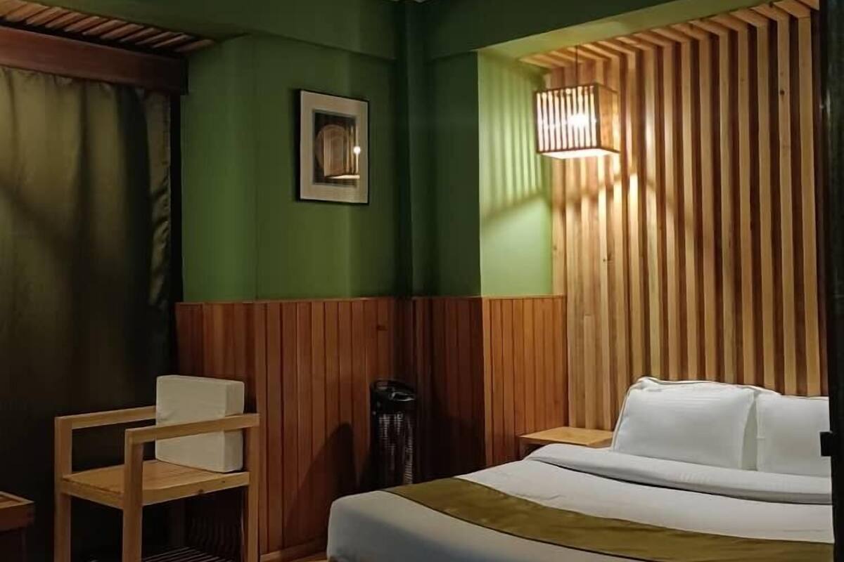 Ein Hotelzimmer mit Bett, einem Sessel, einem kleinen Tisch und einer Wandleuchte.