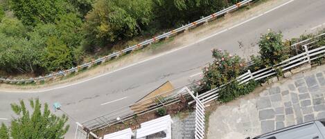 A road curving through a green landscape with a white fence and a parked car.