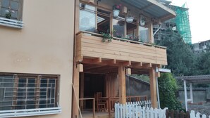 A two-story building with a balcony, wooden railings, and potted plants. - UV INN (Thimphu)
