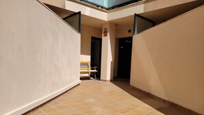A corridor with tiled flooring, a bench, and a door leading to a dark interior. - 5 minutes from the beach, bus terminal and nightlife! (Lloret de Mar)