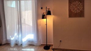 A room with a floor lamp, a wall-mounted light, and a window with sheer curtains. - 5 minutes from the beach, bus terminal and nightlife! (Lloret de Mar)