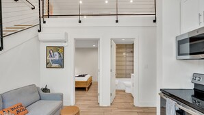 Un intérieur moderne avec un espace de vie de style loft, une cuisine dotée d’un four encastré et une salle de bain avec une douche en verre.