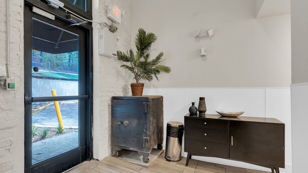 Une pièce avec une porte noire, une petite plante en pot, une armoire bleue et une commode noire avec des tiroirs.