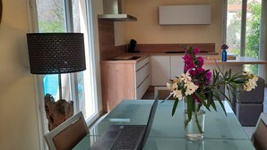 Une cuisine moderne avec une table à manger en verre, un ordinateur portable et un vase rempli de fleurs.