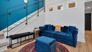 A modern living room with a blue sofa, a bench, and a colorful rug.