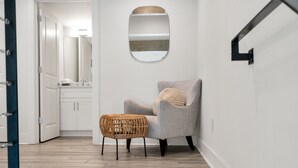 Un bagno moderno con un mobile lavabo bianco, uno specchio e uno sgabello in vimini.