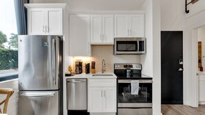 Una cucina moderna con mobili bianchi, elettrodomestici in acciaio inossidabile, un forno a microonde e una lavastoviglie.