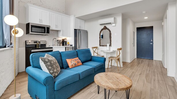 A compact living space with a kitchenette, a blue sofa, a wooden coffee table, and a dining area. - Frenchmen St Gem • Walk to French Quarter (New Orleans)
