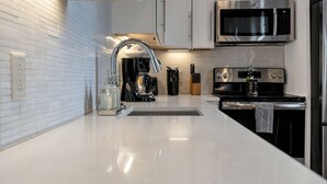 Una cocina moderna con un microondas de acero inoxidable, una cafetera y una estufa.