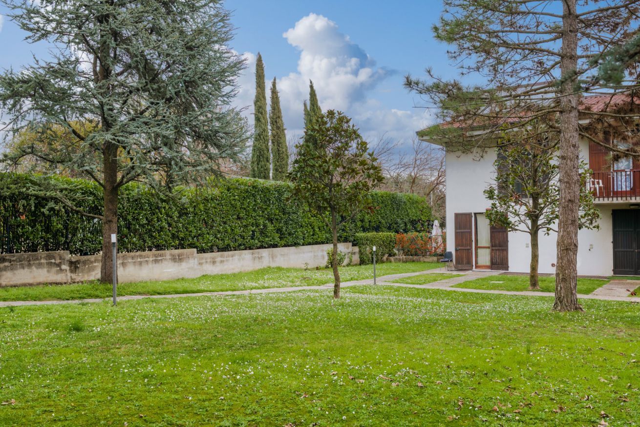 A courtyard with a white building, green grass, and trees.