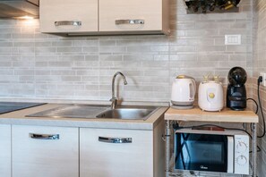 A modern kitchen with a stainless steel sink, a built-in microwave, and a coffee maker on the countertop. - Flower 41 - with patio and air conditioning (Sirmione)