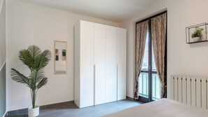 A bedroom with a bed, a wardrobe, a potted plant, a radiator, and a window with curtains.