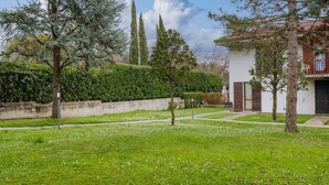 A courtyard with a white building, green grass, and trees.