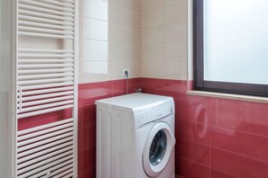 A compact laundry room with a white washing machine and a white radiator.