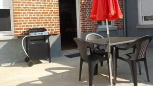 Eine Terrasse mit Grill, Tisch und Stühlen im Freien.