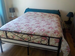 A bed with a floral bedspread, a teal headboard, and two bedside lamps.