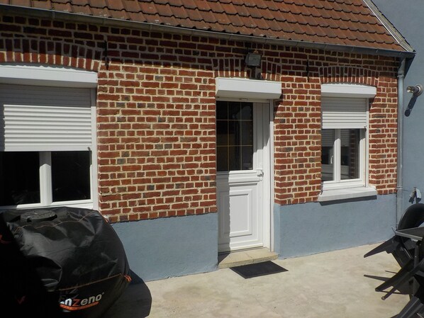 A brick house with a tiled roof, a garage door, and a black grill.