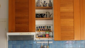 Una cocina con gabinetes de madera, estufa, lavavajillas y salpicadero de azulejos azules.