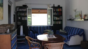 Una sala de estar acogedora con un sofá azul a rayas, una mesa de comedor de madera y una estantería llena de libros.