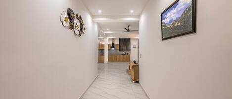 A hallway with a marble floor, a reception desk, a ceiling fan, and a framed landscape painting on the wall.