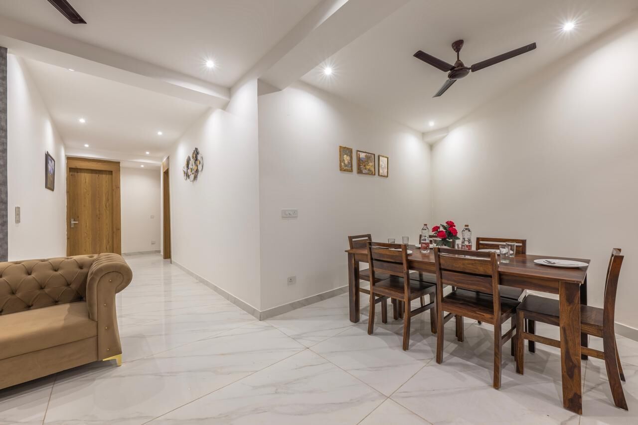 A dining area with a wooden table and chairs, a ceiling fan, and a sofa.