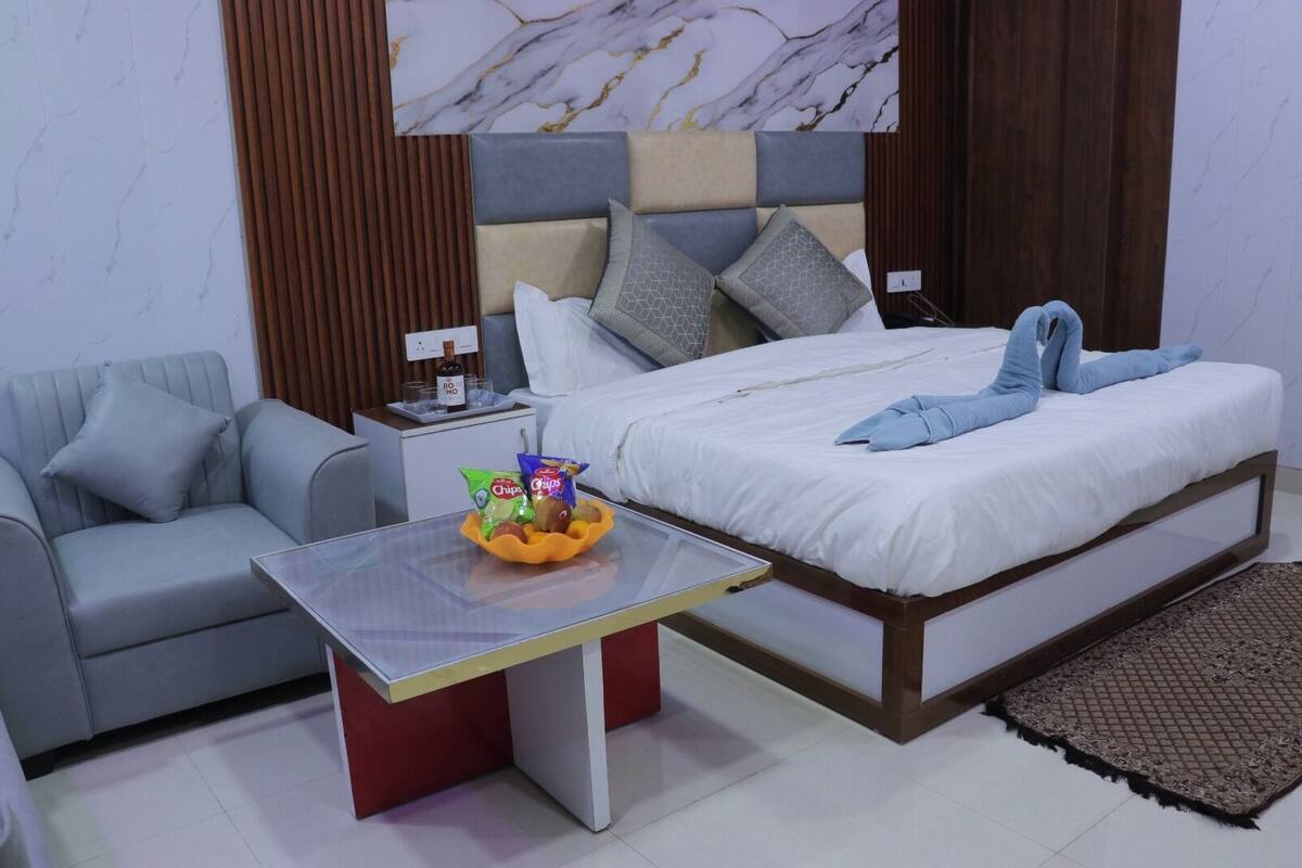 Une chambre avec un lit, un canapé, une petite table avec des collations et un mur décoré d’un motif imitant le marbre.