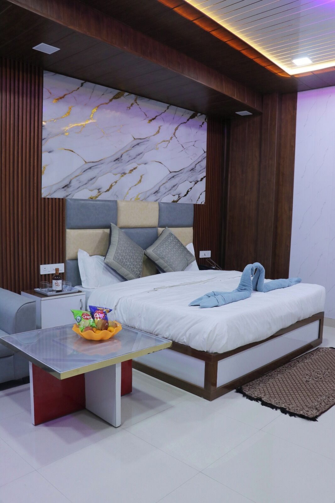 Un dormitorio moderno con cama, mesita de noche y pared con diseño de mármol.
