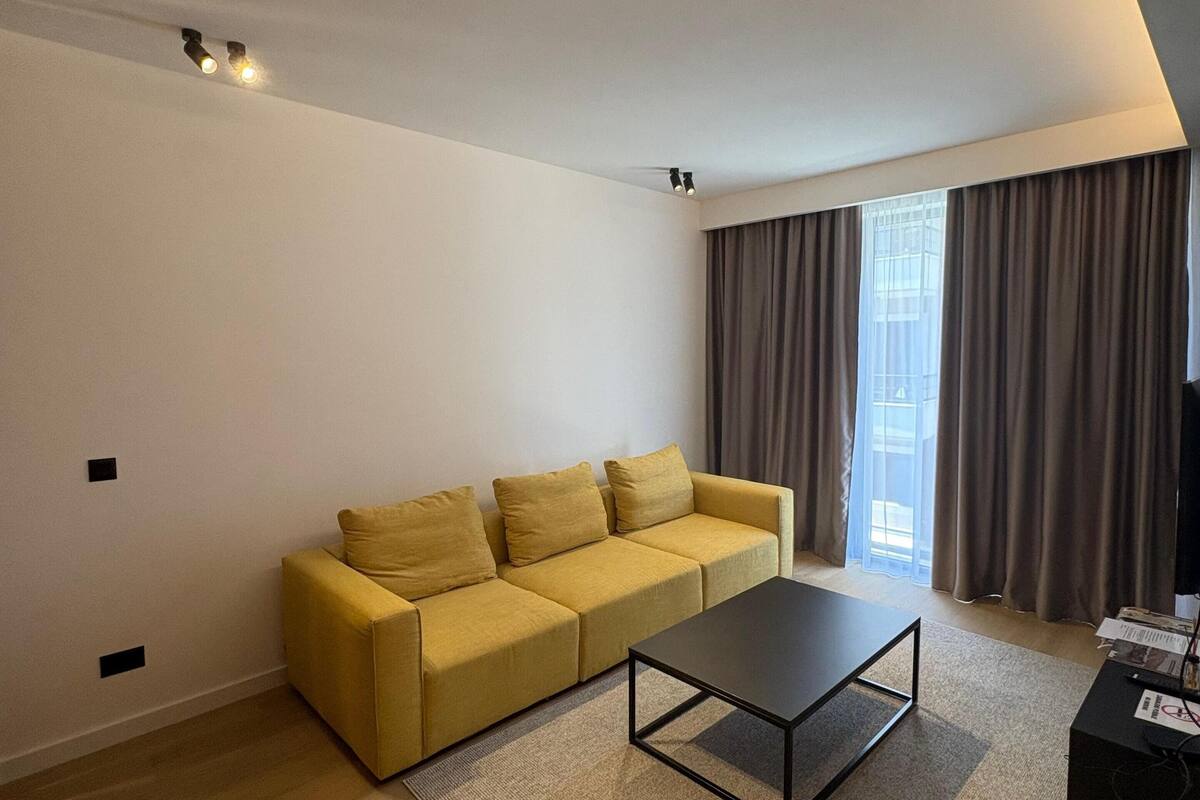 A modern living room with a sofa, a coffee table, and a TV stand.