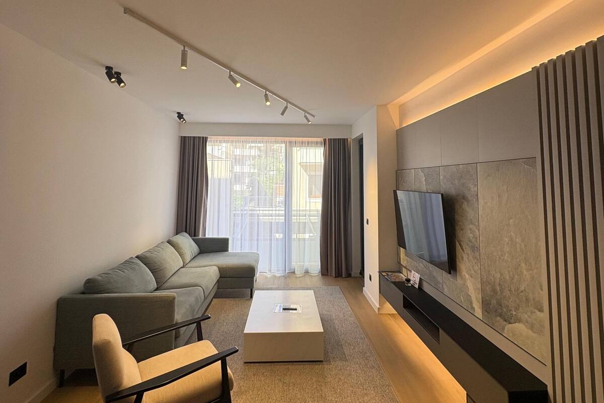A modern living room with a sectional sofa, a coffee table, and a TV mounted on the wall.