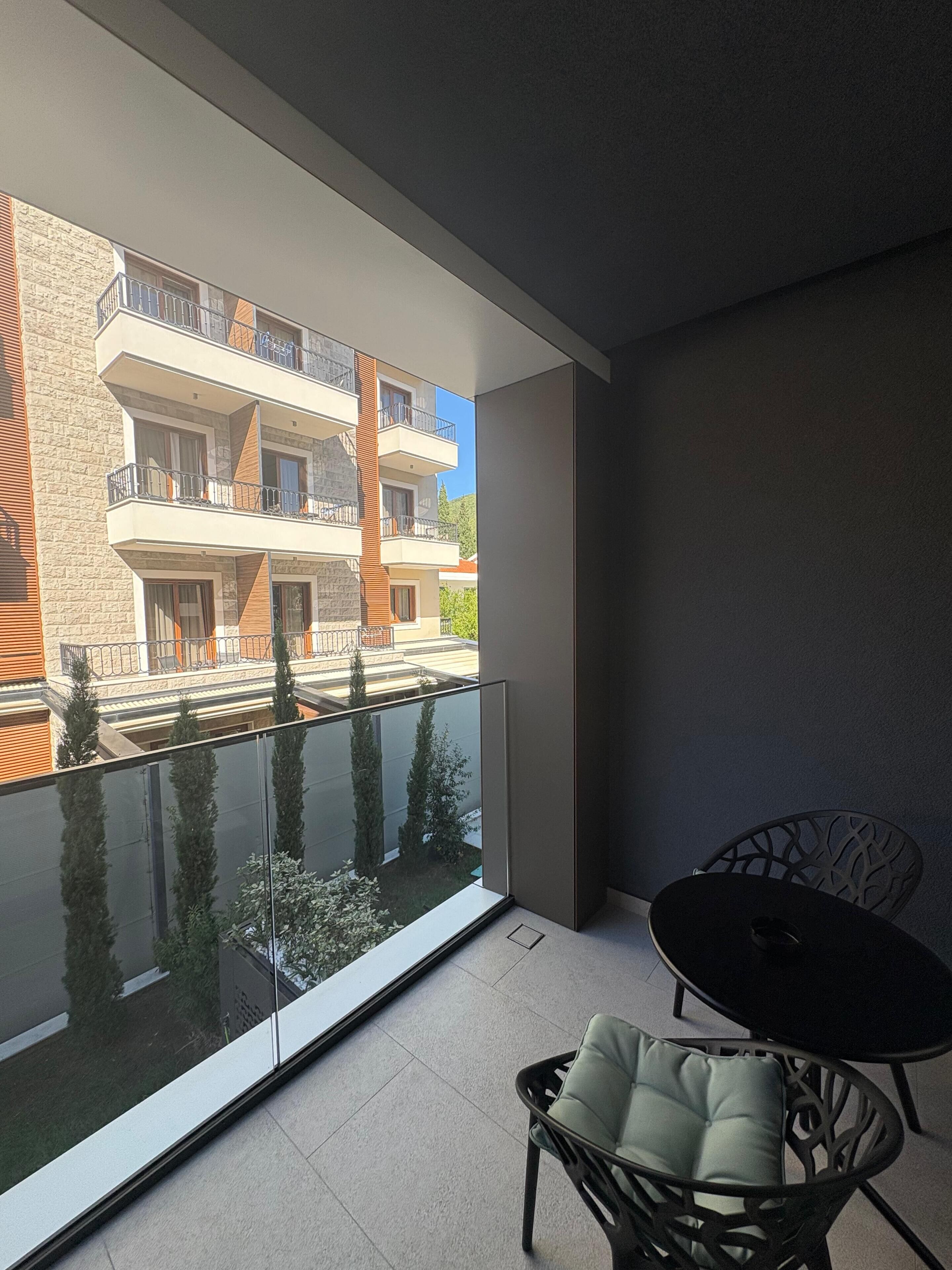 A balcony with a glass door, a small table, and a chair.