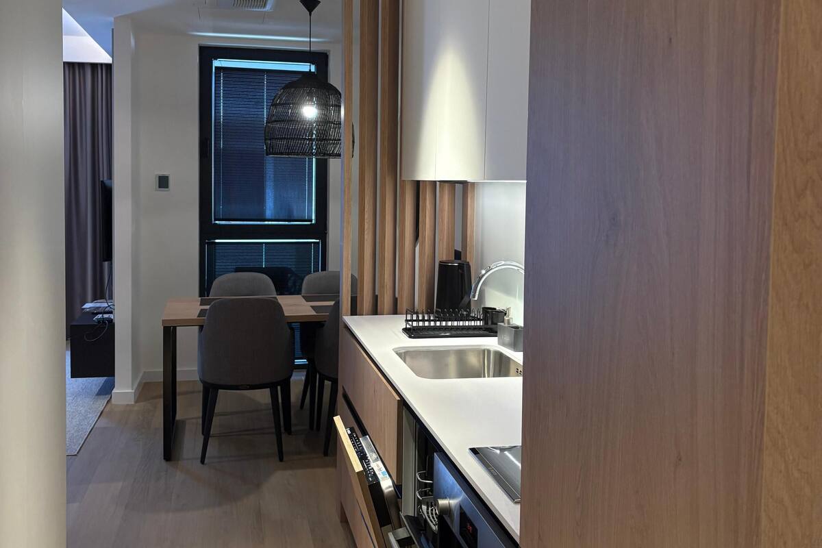 A modern kitchen with a built-in oven, a sink, and a dining area with a table and chairs.