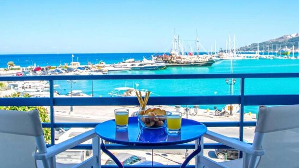 Ein Balkon mit Tisch für zwei Personen, mit Blick auf einen Yachthafen und Boote.