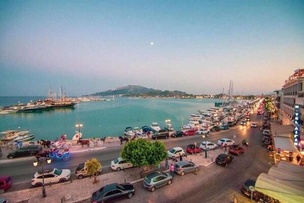 A marina with boats docked, a road with cars, and a hotel on the right.
