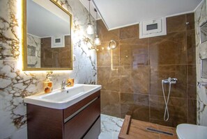 A bathroom with a marble vanity, a shower, and a toilet.