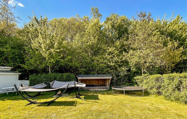 A backyard with a hammock, a wooden deck, and a trampoline.