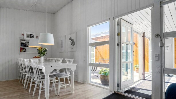 Een moderne keuken met witte kasten, een eettafel met stoelen en een groot raam met uitzicht op de omgeving.