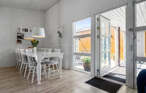 A modern kitchen with white cabinetry, a dining table with chairs, and a large window with a view of the outdoors.