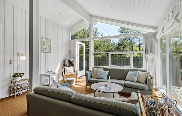 A spacious living room with a large window, a sofa, a coffee table, and a chair.