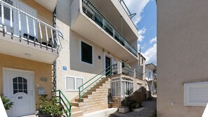A narrow urban street with multi-story buildings, a visible staircase leading to an upper floor, and a clear sky. - 1 bedroom nice apartment in Baska Voda (Baska Voda)