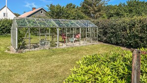 A glass greenhouse structure with a metal frame, a small table, and chairs inside. - 2 bedroom pet friendly home in Læsø (Læsø)