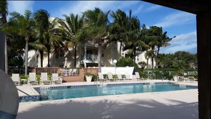 A pool area with lounge chairs and palm trees, surrounded by buildings with balconies. - Charming Coastal Escape (Melbourne)