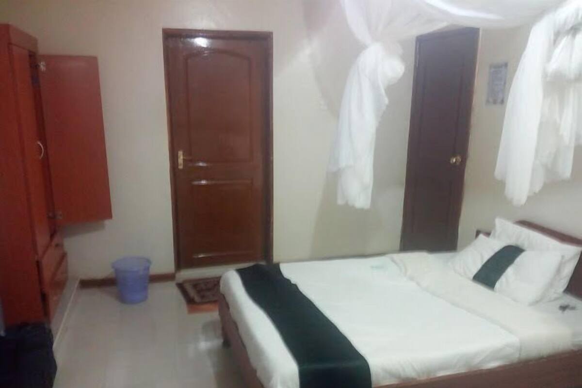 A bedroom with a bed, a wardrobe, and a door.
