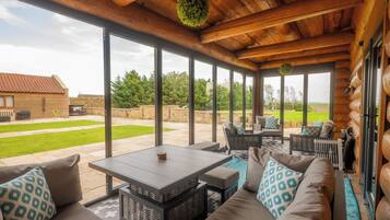 Un espace extérieur aménagé, abrité et doté d’une table et de chaises, de grandes fenêtres et d’une vue sur le jardin arrière.