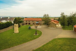 A stone building with a red-tiled roof, surrounded by a well-maintained lawn and a gravel driveway. - Scandinavian Luxury Log Cabin Sleeps 6, Hot Tub, Durham & Bishop Auckland (Oakenshaw, Durham)