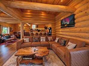 A log cabin interior with a large wooden sofa, a unique coffee table, and a painting of a forest scene. - Scandinavian Luxury Log Cabin Sleeps 6, Hot Tub, Durham & Bishop Auckland (Oakenshaw, Durham)