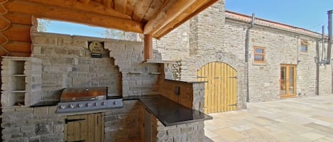 An outdoor kitchen area with a stone wall, a grill, and a wooden door.