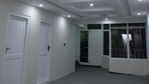 A spacious room with white walls, a ceiling fan, recessed lighting, and a large sliding glass door leading to an outdoor area. - Spacious 9-bedroom hotel suites in beautiful Skardu with WiFi (Skardu)